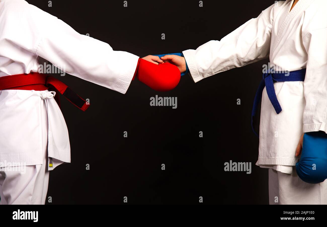 Zwei kleine Karate Frauen in weißen Kimonos, eine in Rot und die andere blau Wettbewerb Ausrüstung schütteln sich die Hände als Zeichen des Respekts vor dem Kampf Aga Stockfoto