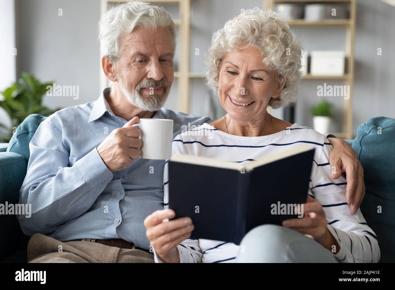 65 s Ehegatten zu Hause lesen Buch trinken Trinken ausruhen Stockfoto