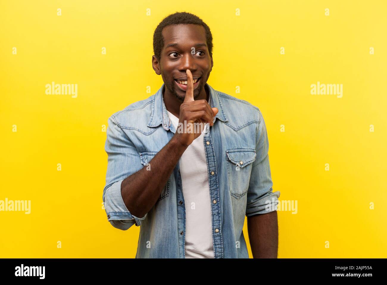 Bitte Schweigen. Portrait von fröhlichen stattlicher Mann in Jeans casual Shirt und deutete mit dem Finger auf seine Lippen, ruhig zu sein, mit der Bitte um Geheimhaltung. indo Stockfoto