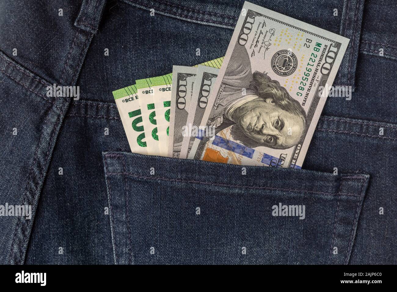 Viele Dollar und Euro aus der Gesäßtasche der Jeans kleben Schuß Nahaufnahme. Stockfoto