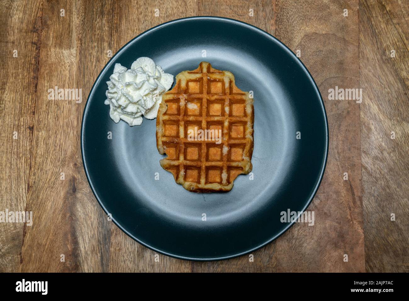 Mit hausgemachten belgischen Waffeln auf einem Teller. Mit Schlagsahne auf der Seite. Ansicht von oben Stockfoto