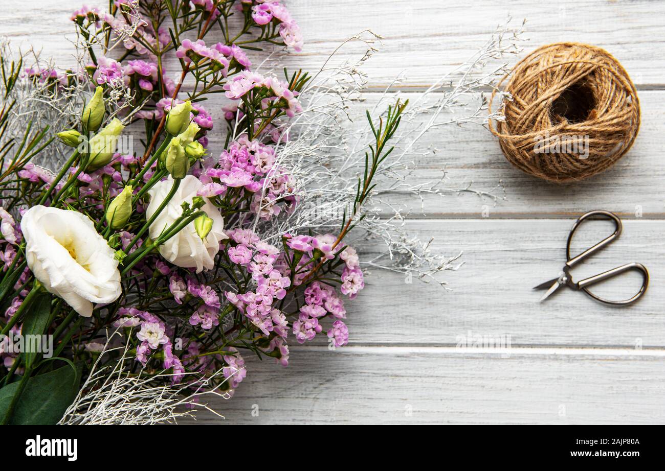 Arbeitsplatz: Florist Blumen und Zubehör auf einem whitw Holztisch. Flach. Stockfoto