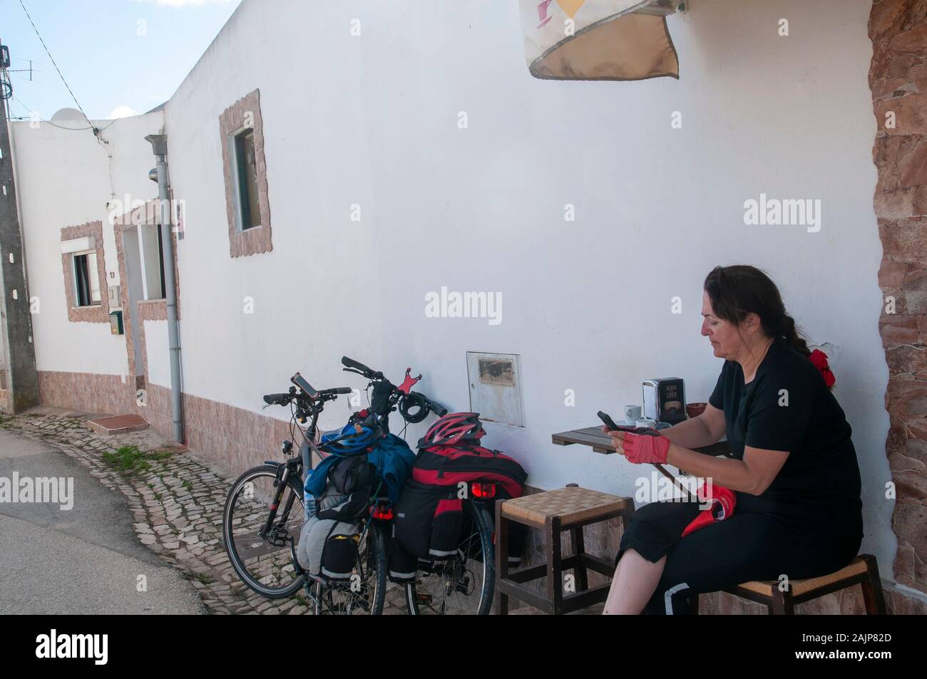 Fahrrad Touristen in Ruhe in einem kleinen Cafe in einem malerischen blauen und weißen Häuser eine Straße in einem kleinen Ort in der Gemeinde von Obidos, Portugal Stockfoto