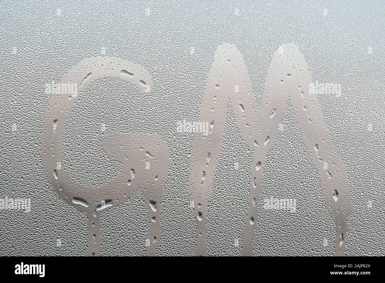 Nasse Fenster Glas Oberfläche mit GM Buchstaben, guten Morgen Nachricht, Symbol Stockfoto