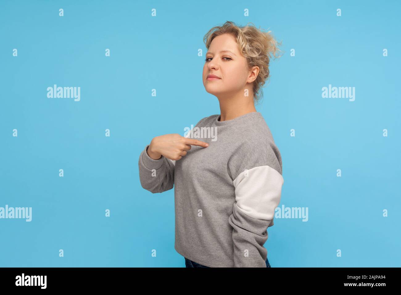 Das bin ich! Egoistisch hochmütige Frau mit kurzen lockiges Haar in Sweatshirt selbst zeigt, Gefühl überheblich arrogant, stolz auf persönliche Leistungen. Stockfoto