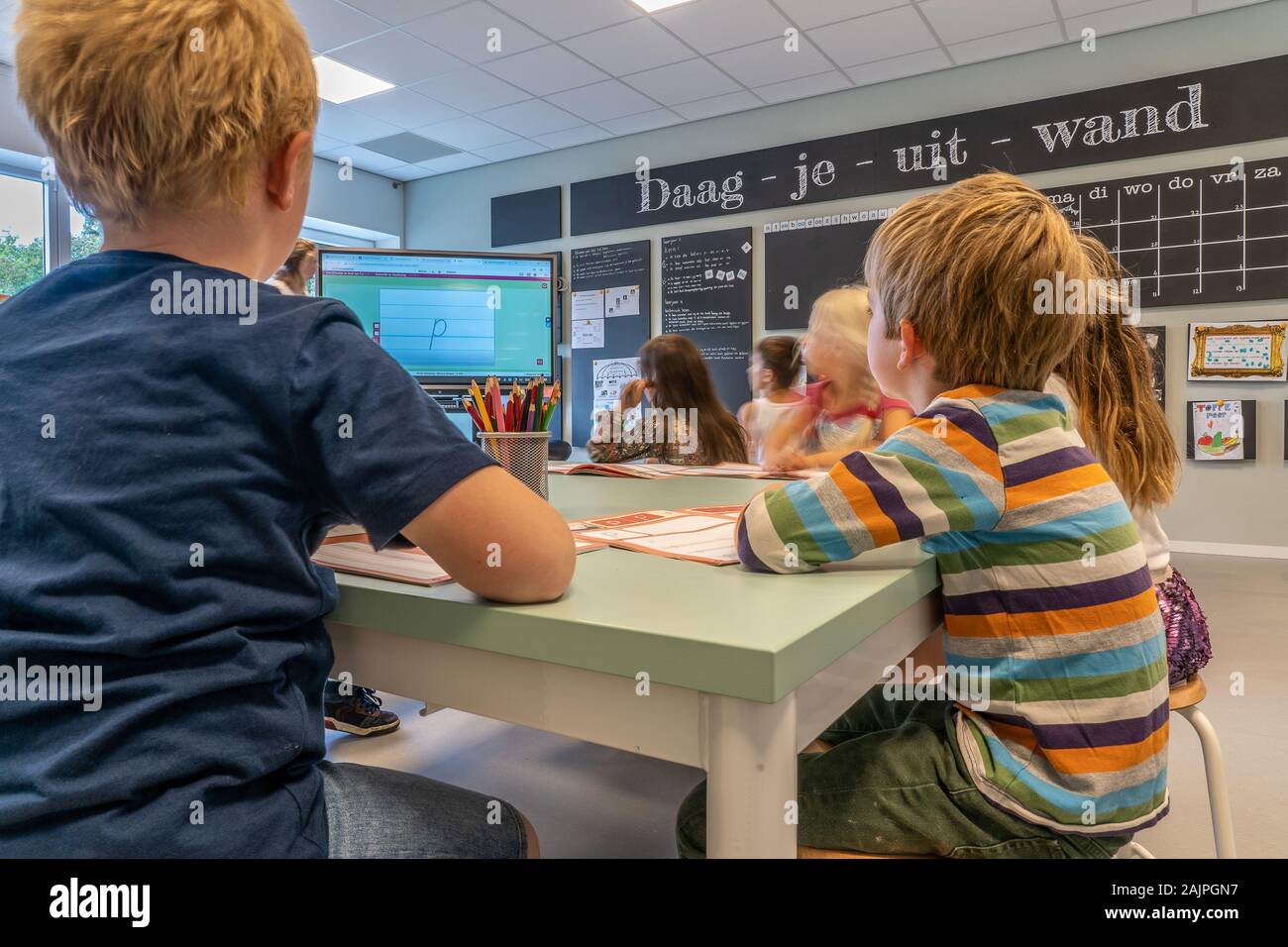 NIJMEGEN/Niederlande - September 13, 2019: Kinder im Klassenzimmer sitzen, hören auf die teacherBlack boaed und Smart Board sichtbar Stockfoto