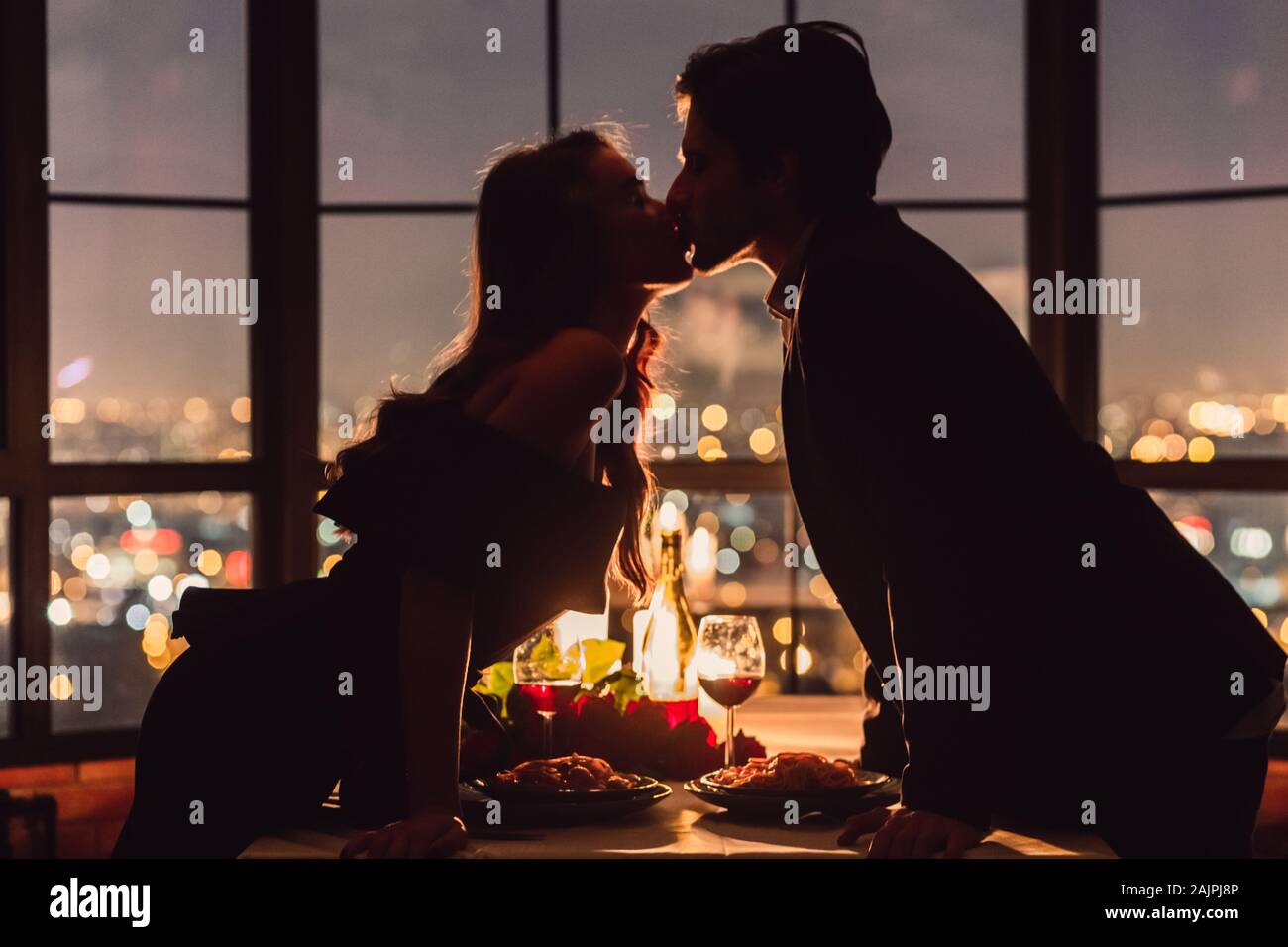 Paar küssen Auf Panoramafenster Hintergrund mit Blick auf nigth Stadt. Romantischer Ort für romantische Abend Konzept Stockfoto