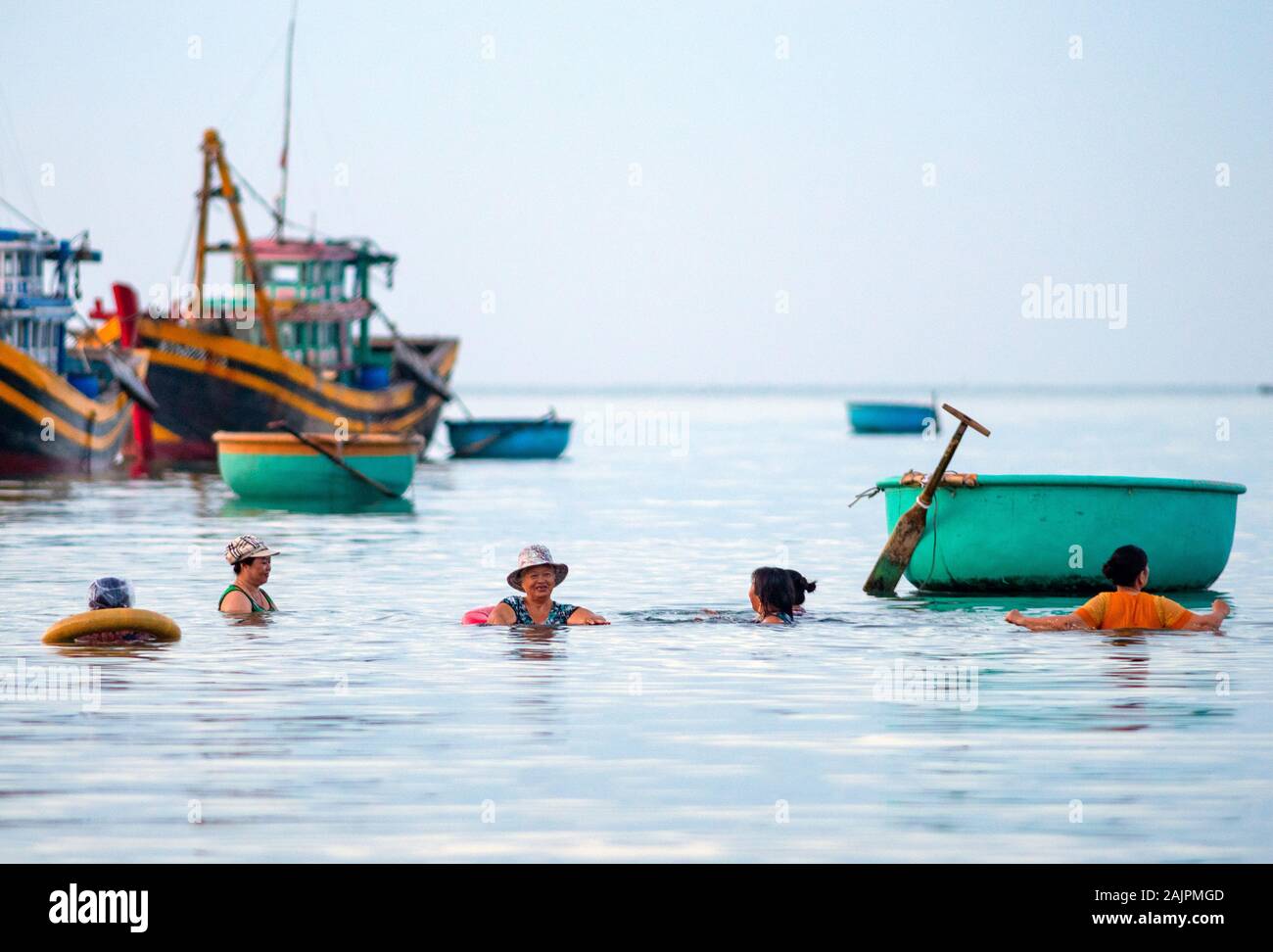 Asiatische Frauen baden in der Nähe der Boote Stockfoto
