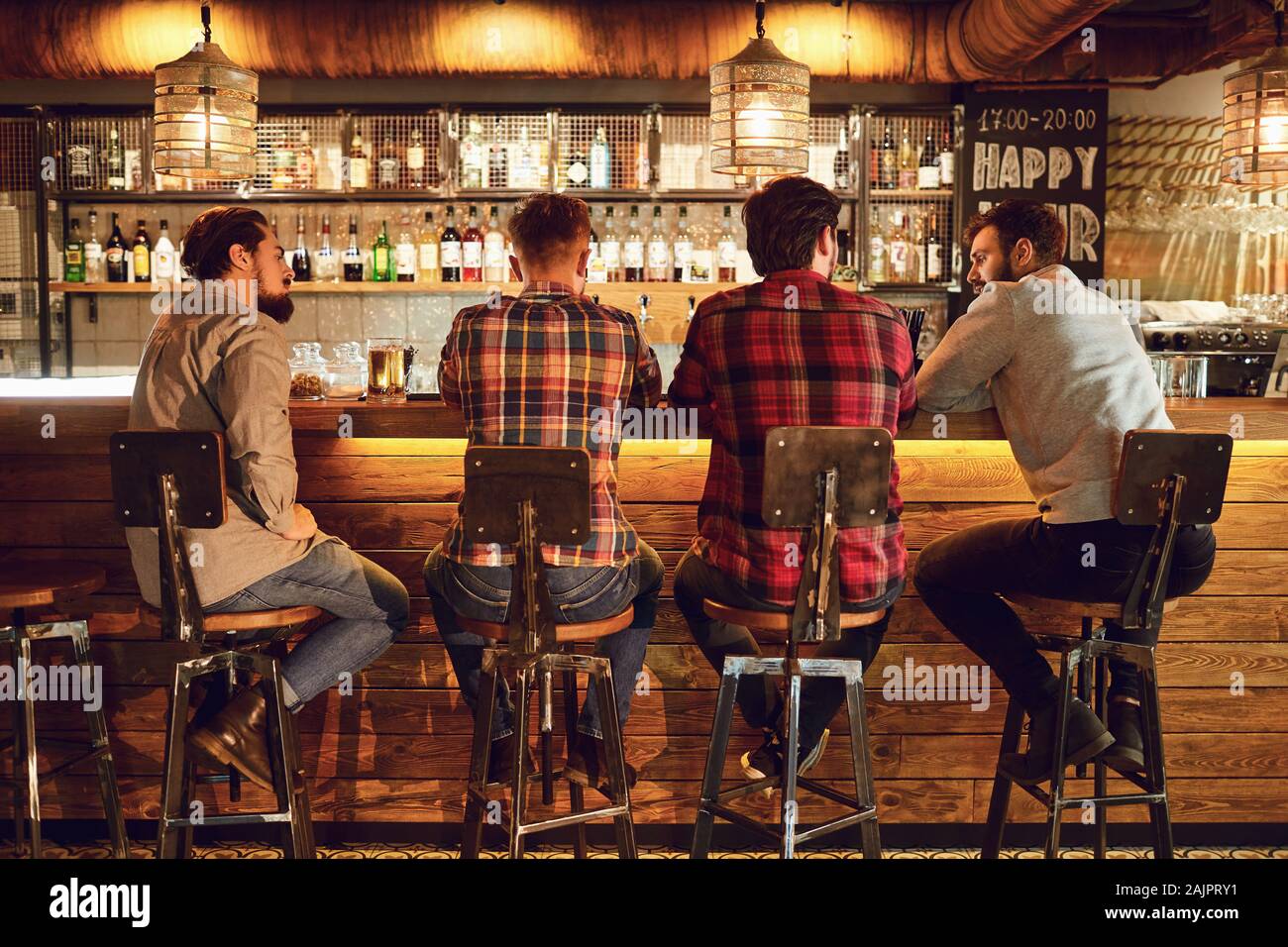 Rückansicht Freunde sitzen auf Stühlen im Gespräch an der Bar in einer Bar. Stockfoto