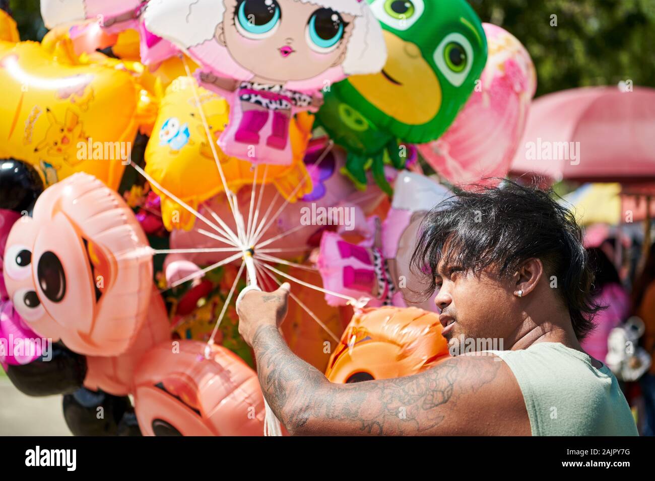 Ibajay, Aklan, Philippinen: Jungen tätowierten Mann verkauf von Helium Spielzeug Ballone in einem Park an der jährlichen Ati-Atihan-Festival gefüllt Stockfoto