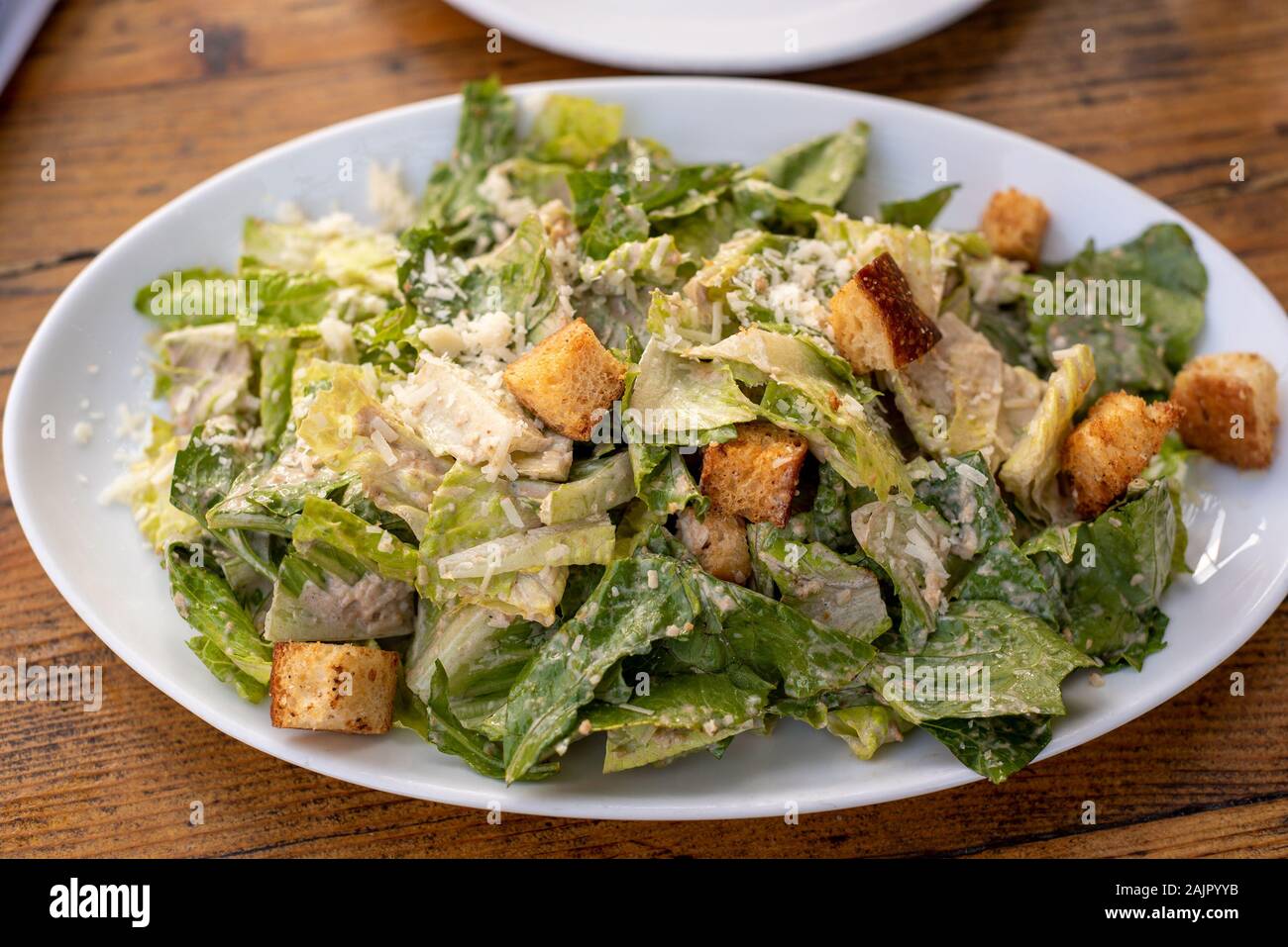 Kopfsalat und Croutons garniert mit geriebenem Käse, Cezar Salat auf weiße Platte über Holz- Tabelle Stockfoto