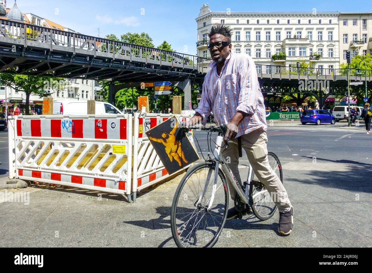 Deutschland Berlin Kreuzberg Alltag, Mann auf einem Fahrrad mit einem Bild von fetten Jesus Schlesisches Tor, Berlin City People Afro American man Berlin Bike Stockfoto