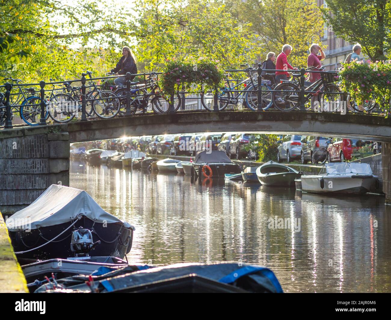 Ruhiger Abend Szene mit Menschen passieren einer Brücke über dem Amsterdamer Bloemgracht in der Altstadt von der niederländischen Stadt Viertel Jordaan. Stockfoto