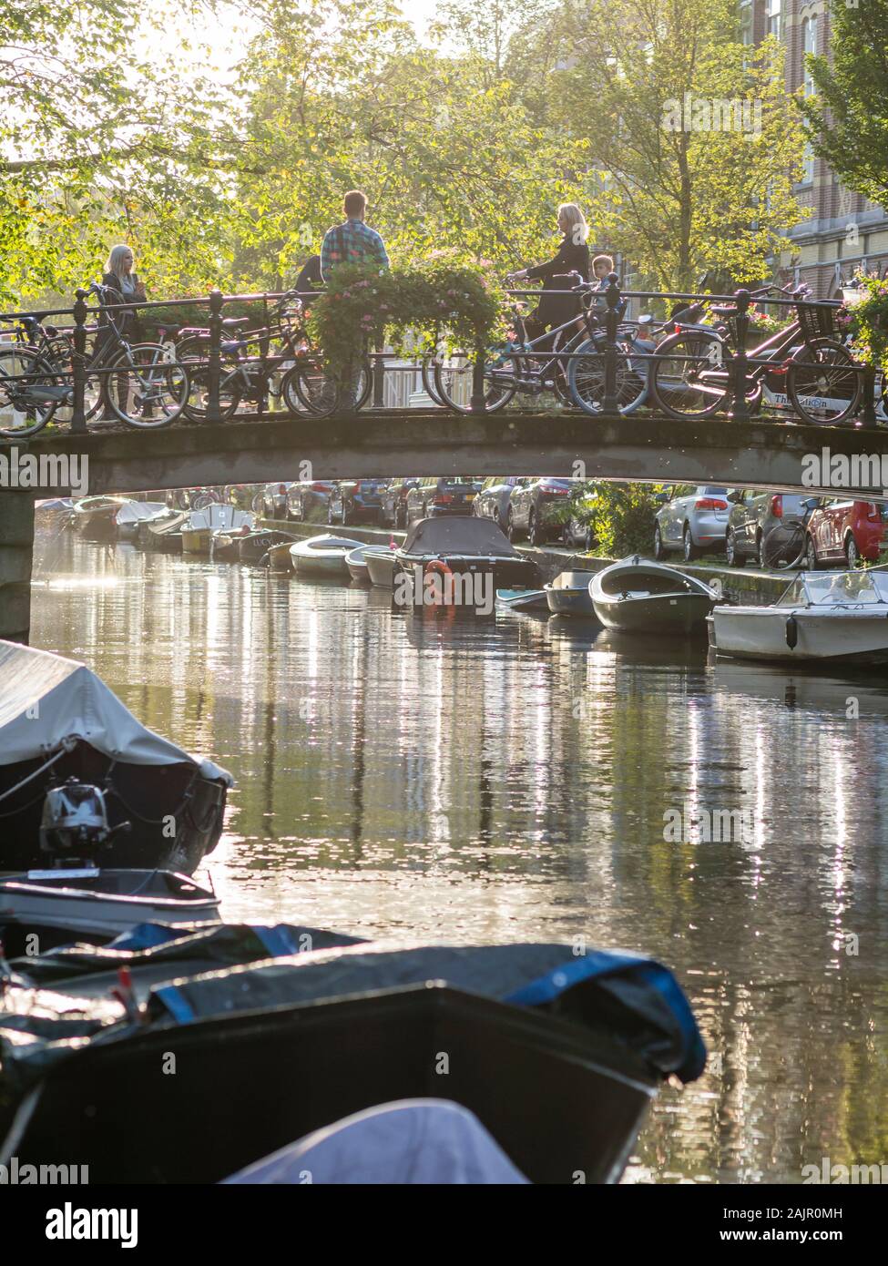 Ruhiger Abend Szene mit Menschen passieren einer Brücke über dem Amsterdamer Bloemgracht in der Altstadt von der niederländischen Stadt Viertel Jordaan. Stockfoto