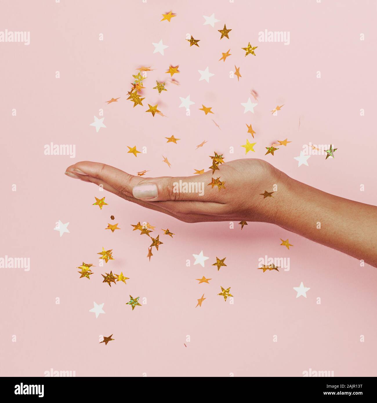 Gold Konfetti Sterne Dekoration in weiblicher Hand auf Pastell rosa Hintergrund Stockfoto