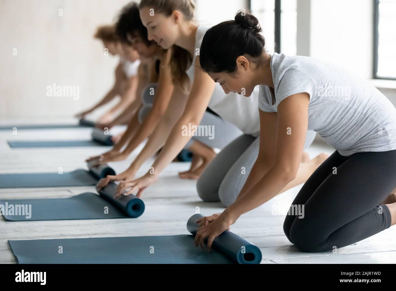 Unterschiedliche Menschen rolling Matten, die Vorbereitung auf die Gruppe Yoga Lektion Stockfoto