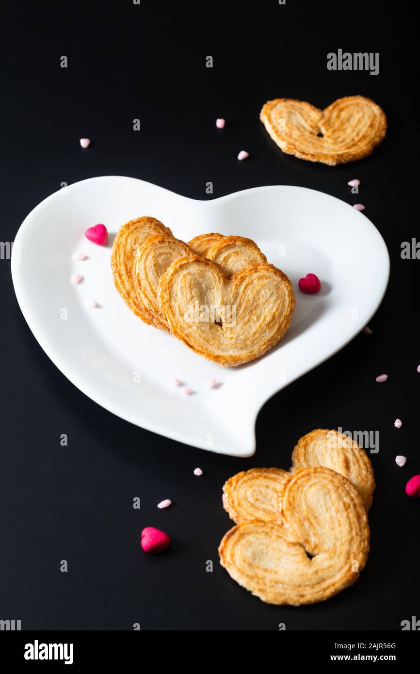 Valentine Dessert essen Konzept Blätterteig Herzen in weißer Keramik Herz Form auf schwarzen Hintergrund mit Kopie Raum Stockfoto