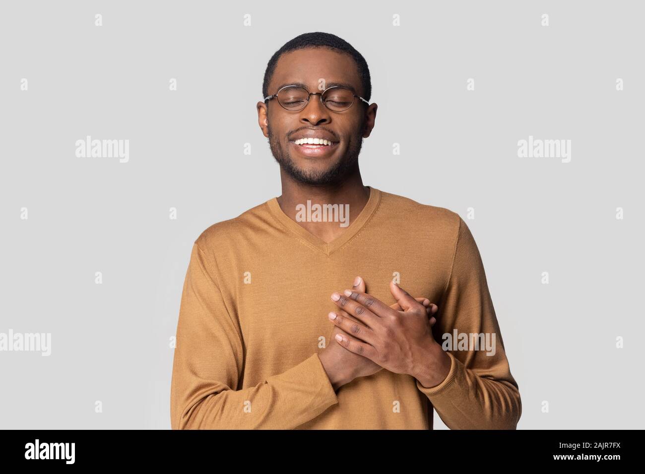 Afrikanische Kerl hält die Hände auf der Brust mit Dankbarkeit studio Shot Stockfoto