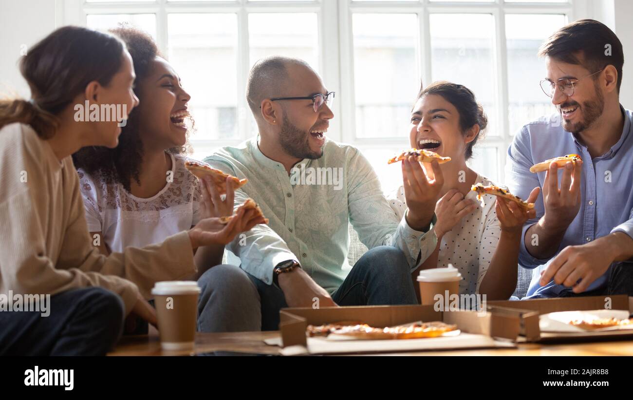 Multiethnischen tausendjährigen Freunde Pizza zu Hause essen Überglücklich Stockfoto