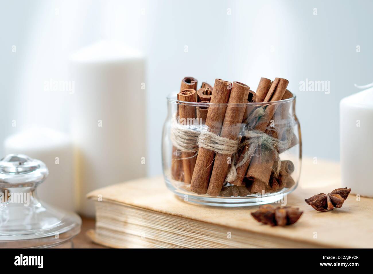 Zimtstangen in Glas, Anis Sterne, Kerzen, vintage Buch auf alten rustikalen Holzmöbeln im Landhausstil Hintergrund. Gemütliche noch leben. Stockfoto