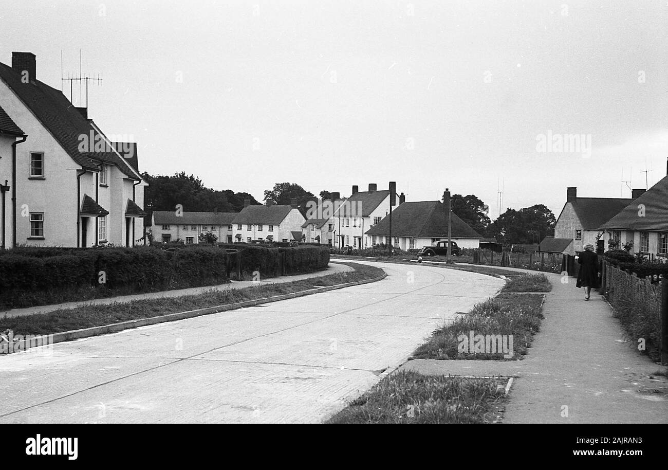 1950er Jahre, historisch, eine ruhige, in den 1930er Jahren erbaute Vorstadt-Wohnanlage mit Gehwegen mit Grasverden, weiß gewaschenen zweistöckigen Cottages und Einebenenwohnungen, England, Großbritannien. Stockfoto