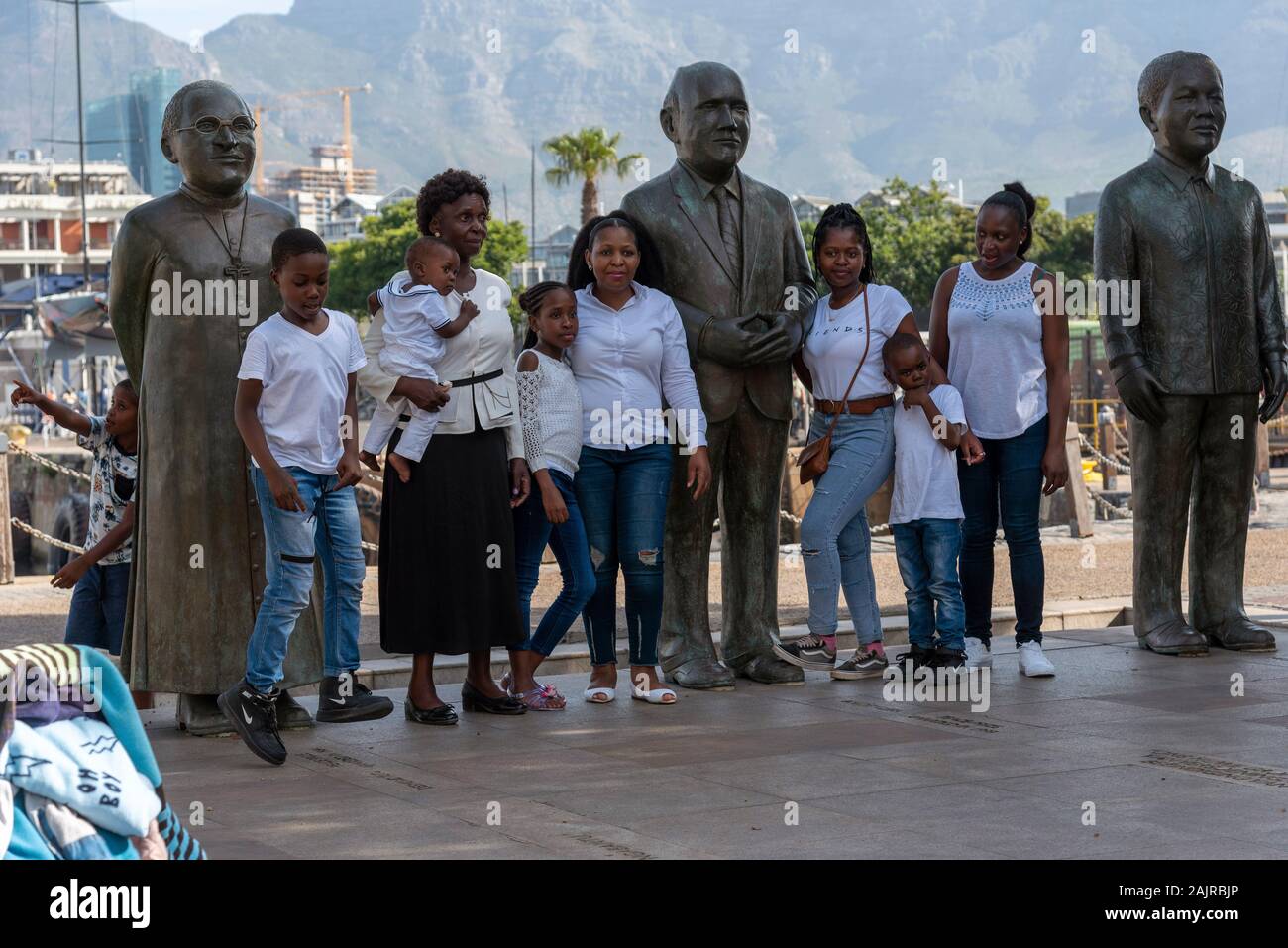 Kapstadt, Waterfront, Südafrika. Dezember 2019. Familie Mitglieder bei einem Besuch in Kapstadt Waterfront Bereich pose mit drei großen Südafrikaner. Stockfoto