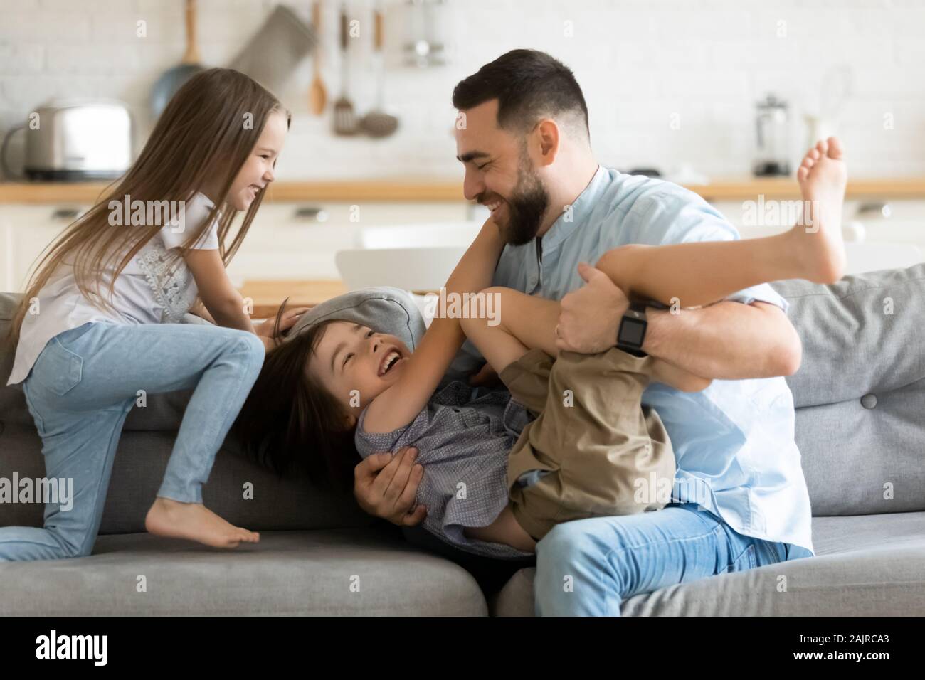 Aktive heiter Vater spielen mit den Kindern auf der Couch zu Hause Stockfoto