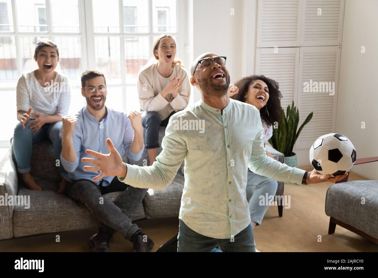 Überglücklich multiethnischen Freunden Fußball zu Hause Stockfoto
