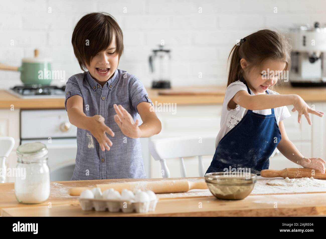 Geschwister spielen mit Mehl Spaß zu Hause in Kochen Stockfoto