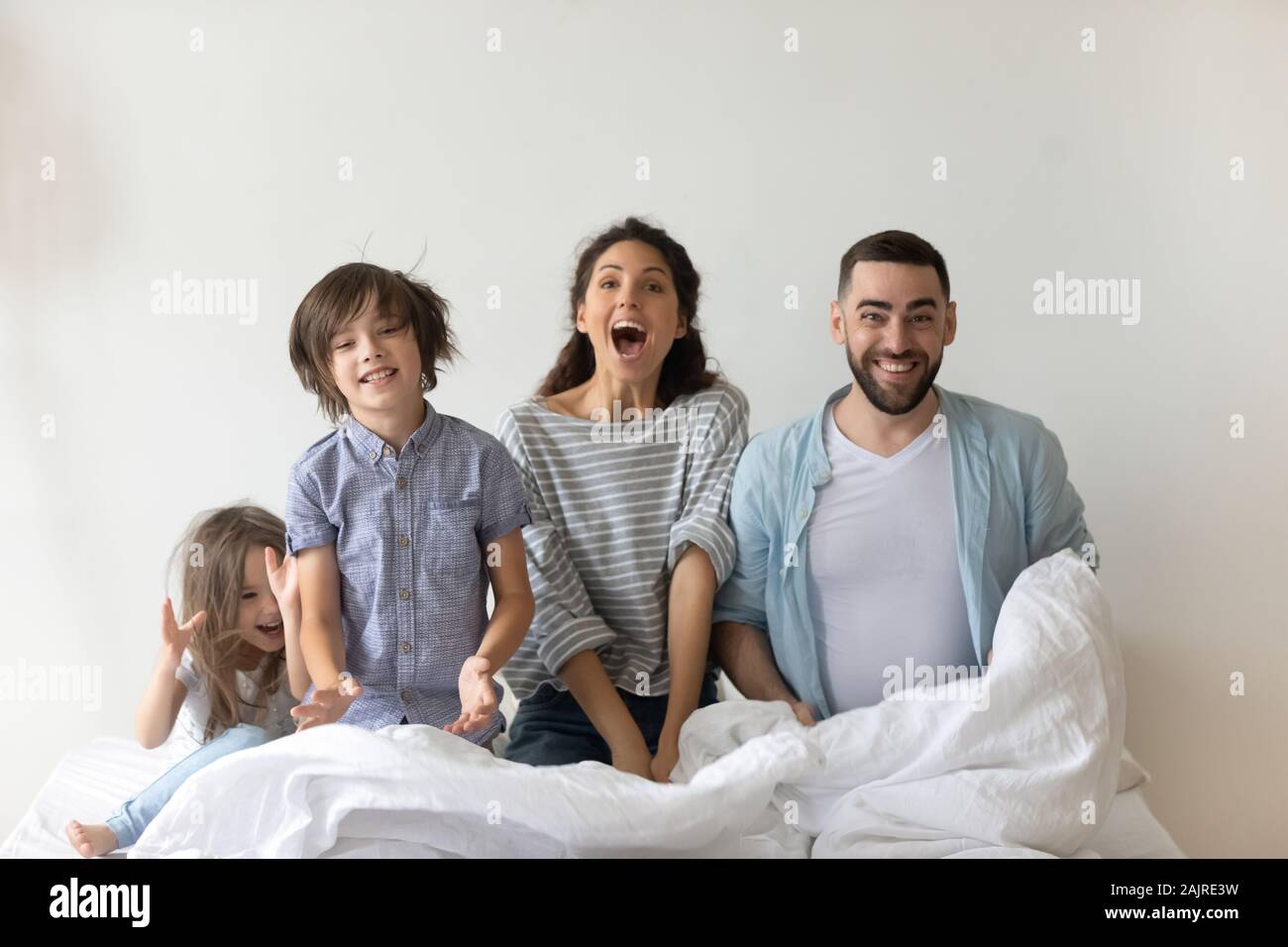 Freundliche Familie mit Kindern an der Kamera auf dem Bett sitzt auf der Suche Stockfoto