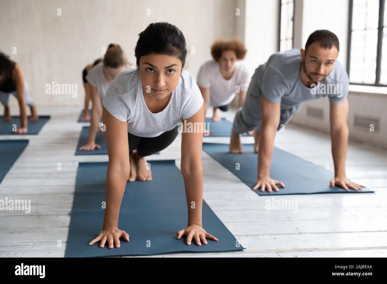 Unterschiedliche Menschen üben Yoga in der Gruppe Lektion, Plank Übung Stockfoto