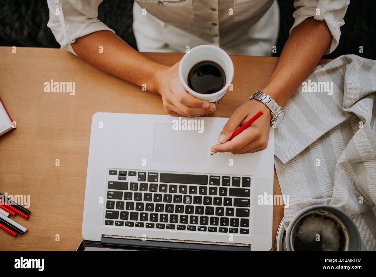 Junge Geschäftsfrau trinkt Kaffee und arbeitet auf Laptop in ihr Stockfoto