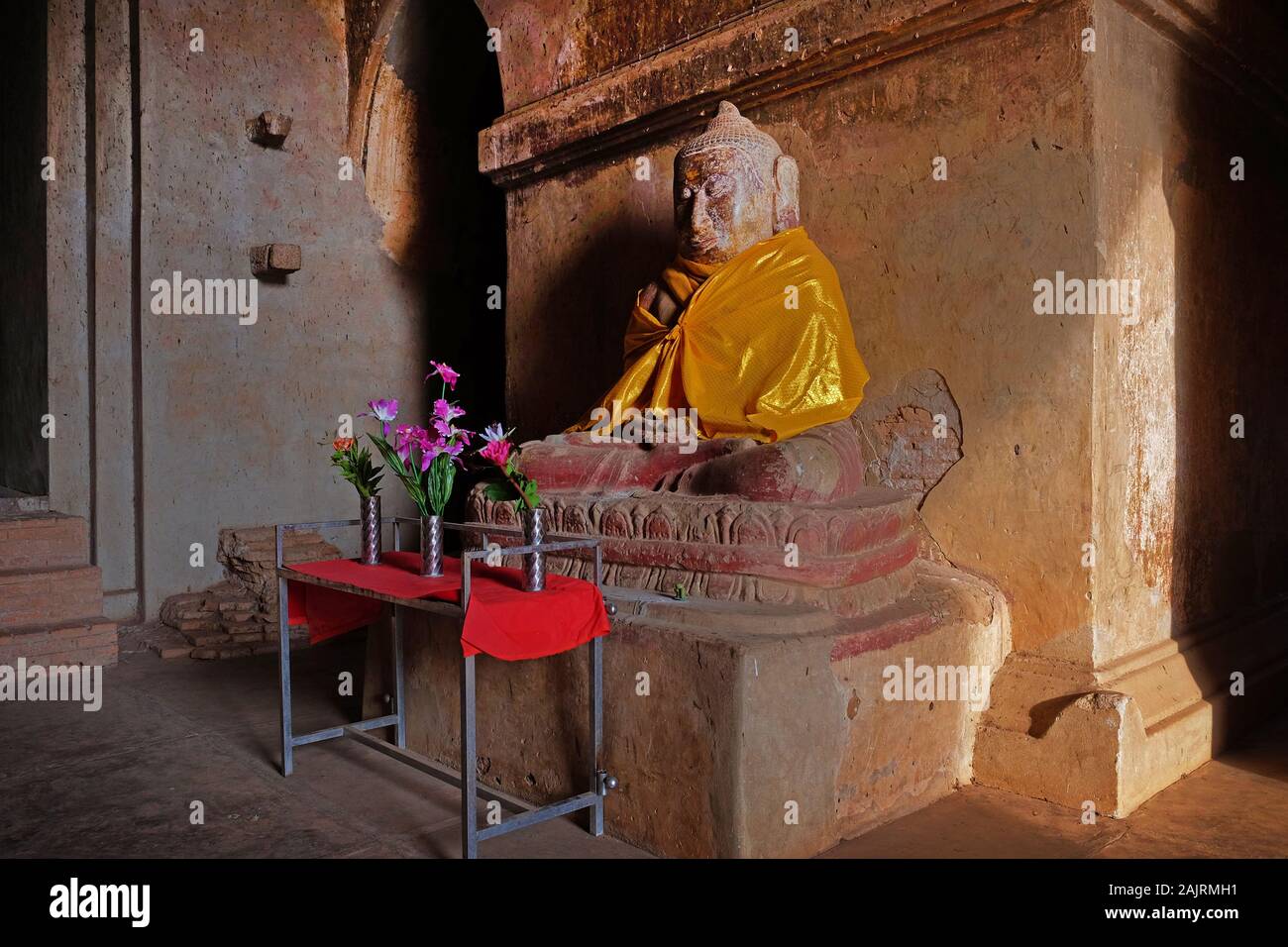Buddha Statue in einem Tempel in Bagan, Myanmar, in orange Textilien mit bunten Motiven. Stockfoto