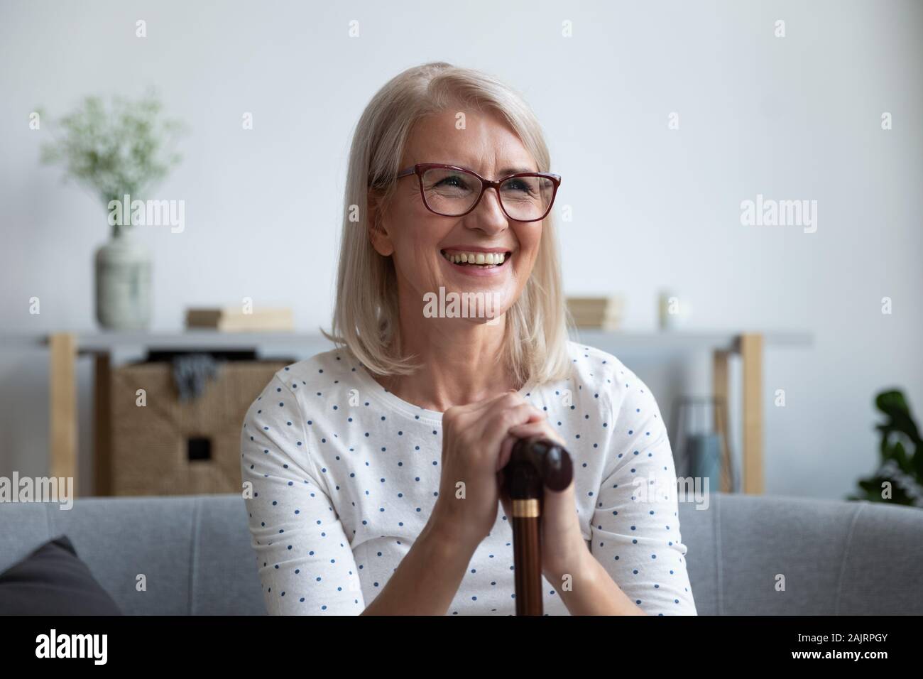 Lächelnde ältere Frau mit Zuckerrohr zu Hause fühlen positive Stockfoto