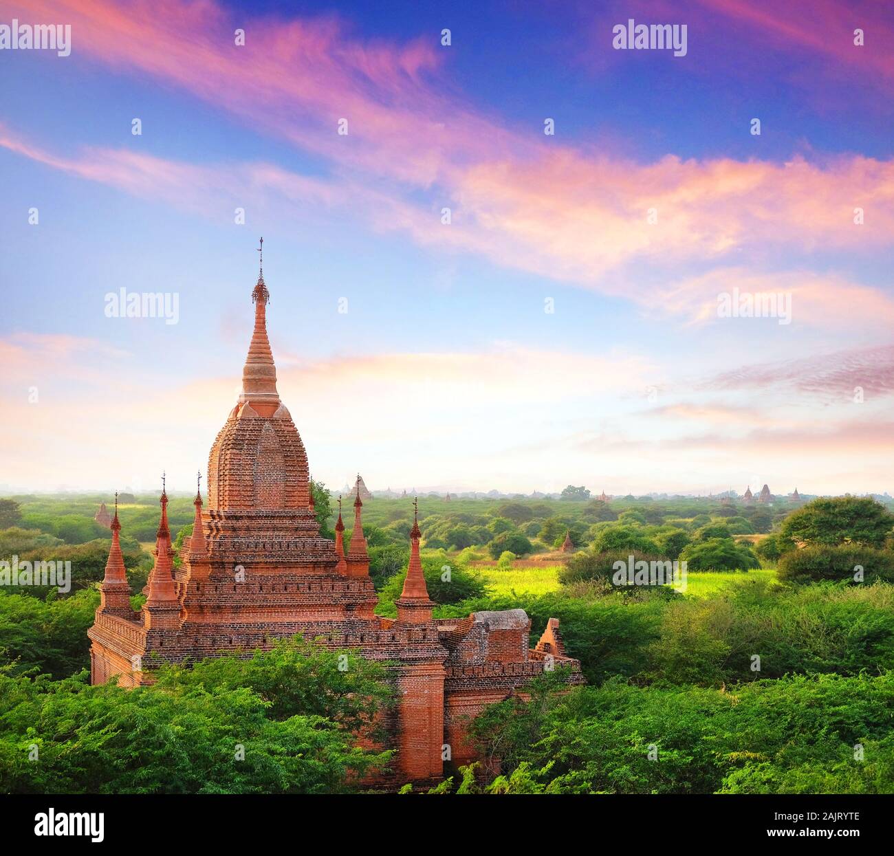 Farbenfrohe blaue und rote sunrise Himmel über alte buddhistische Tempel von grüner Vegetation im Old Bagan, Myanmar umgeben. Stockfoto