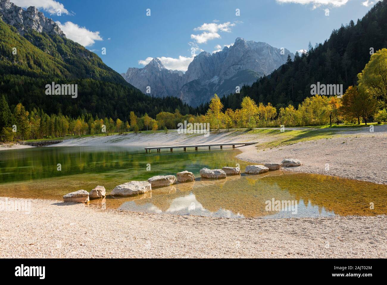 Die alpinen See Jasna mit großen Felsen im Wasser und von Bäumen im Herbst Farben und Alpen Berge in der Nähe von Kranjska Gora in Slowenien umgeben. Stockfoto