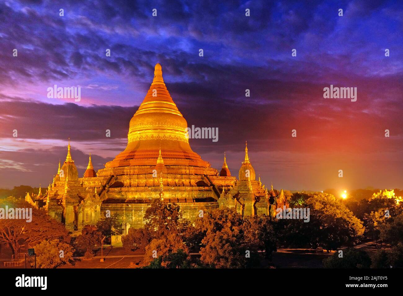 Sunrise Himmel durch dramatische Wolken über alte buddhistische Tempel von Vegetation in Alt Bagan, Myanmar umgeben. Stockfoto