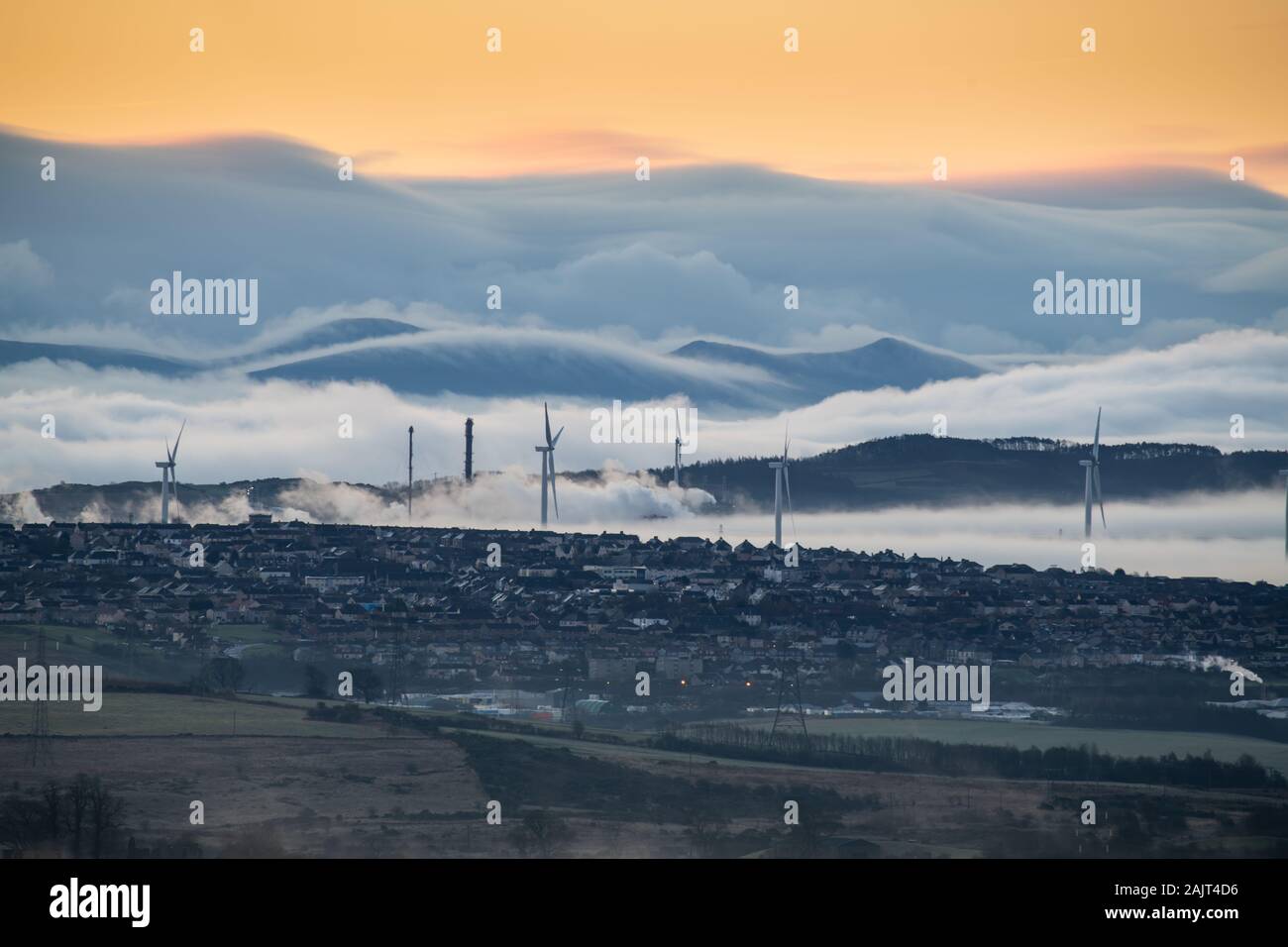 Wind Farm, petrochemische Anlagen und kleine Stadt mit Pentland Hills und sanften Nebel im Hintergrund. Stockfoto