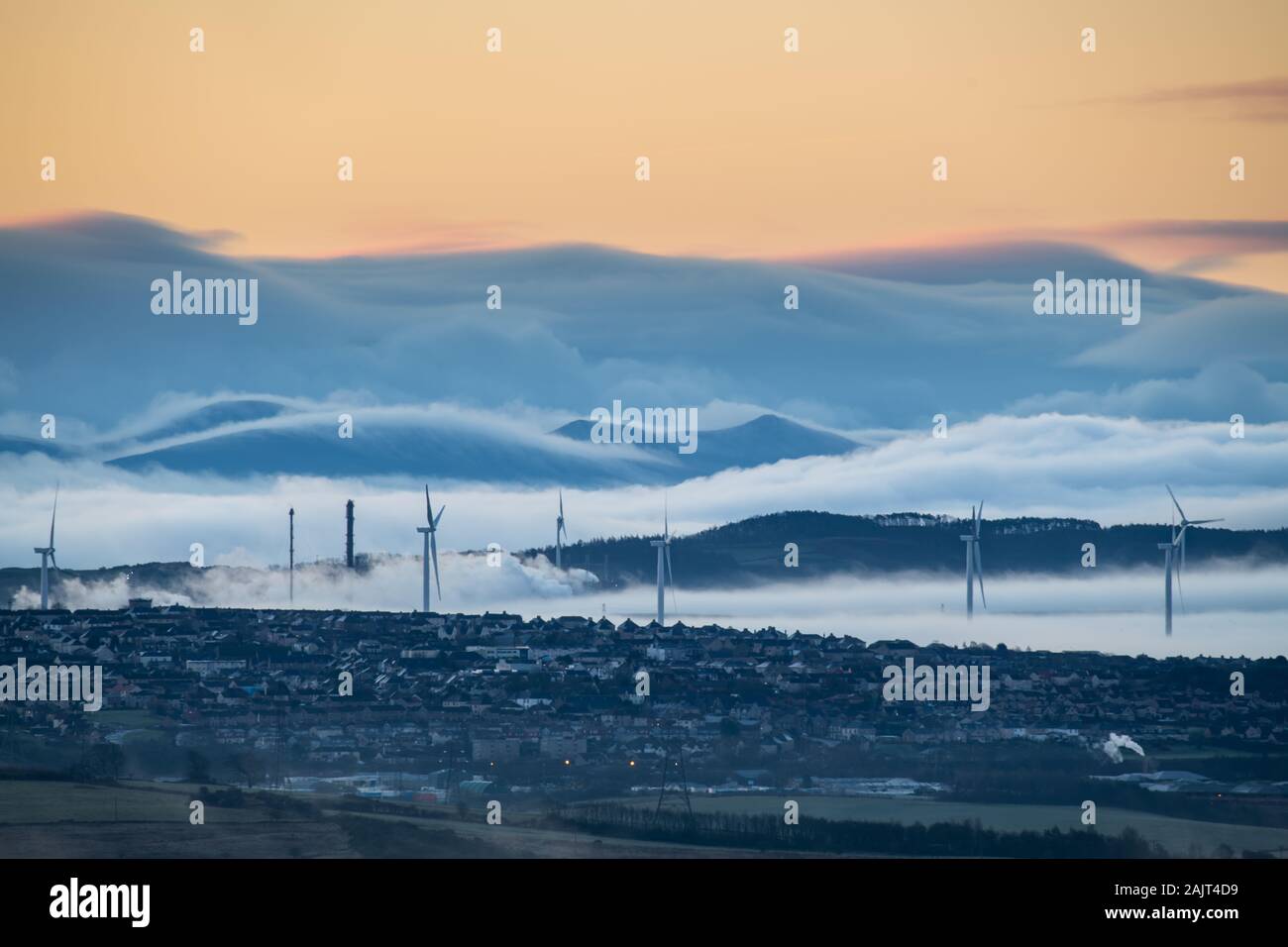 Wind Farm, petrochemische Anlagen und kleine Stadt mit Pentland Hills und sanften Nebel im Hintergrund. Stockfoto