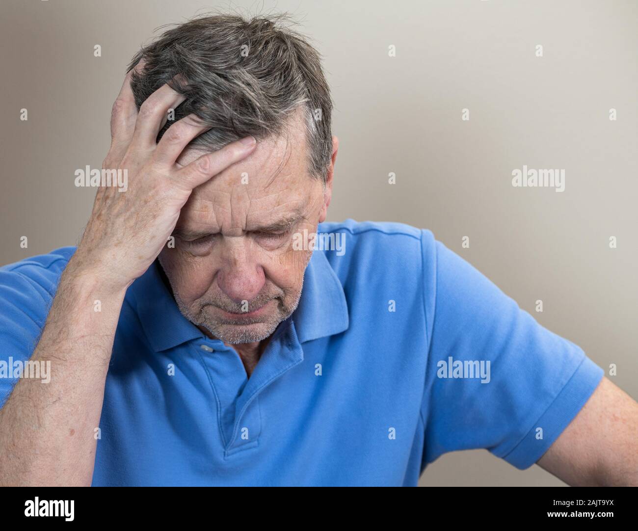 Kopf und Schultern Portrait eines älteren kaukasischen Mann mit Kopf in den Händen und Suchen gedrückt Stockfoto