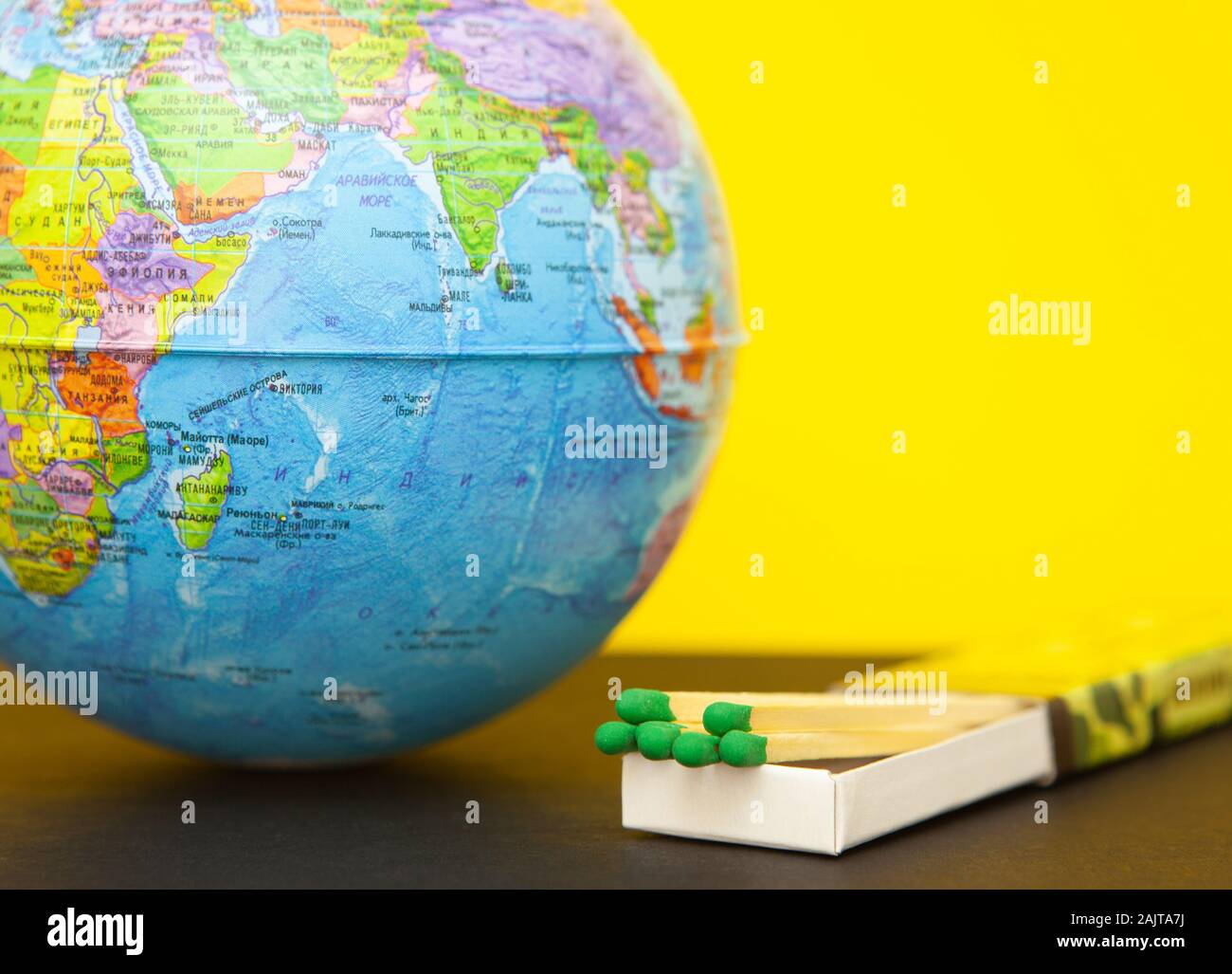 Streichholz und Weltkugel auf gelbem Hintergrund, Konzept zur Rettung des Planeten von Feuer Stockfoto