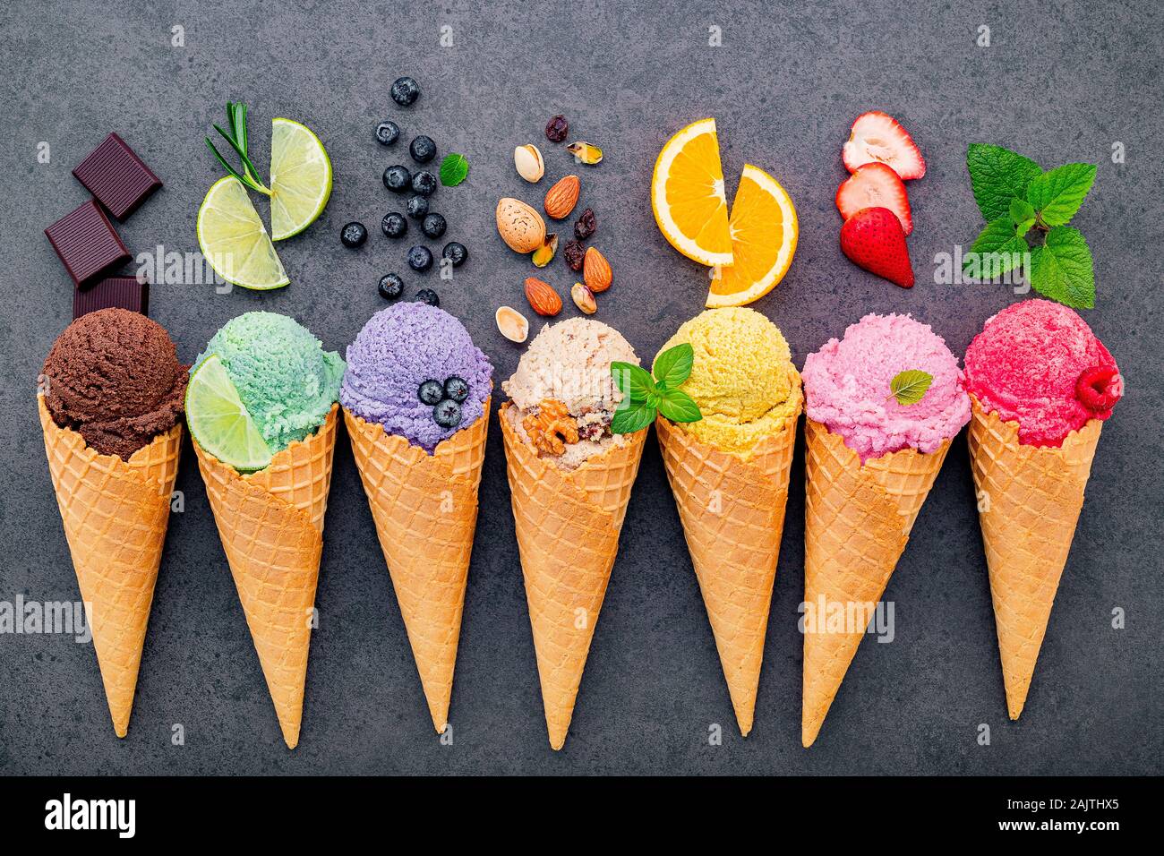 Verschiedene Eissorten Aroma in der Kegel Blueberry, Kalk, Pistazien, Mandeln, Orangen, Schokolade, Vanille und Kaffee auf dunklem Stein gesetzt. Summe Stockfoto