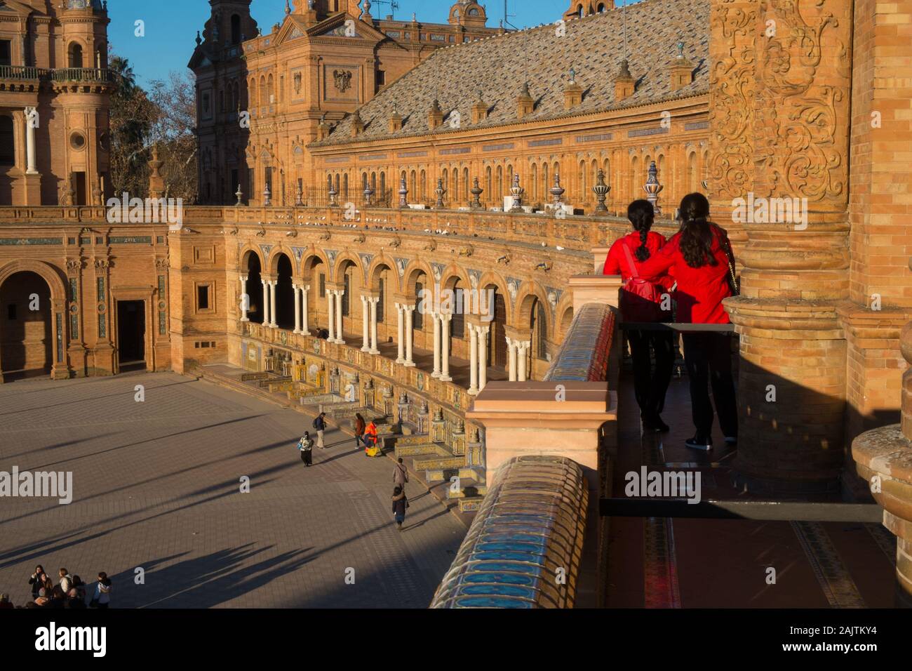 Zwei Frauen in roten Hemden stehen auf einem Balkon an der Plaza Espana, Sevilla, Spanien Stockfoto