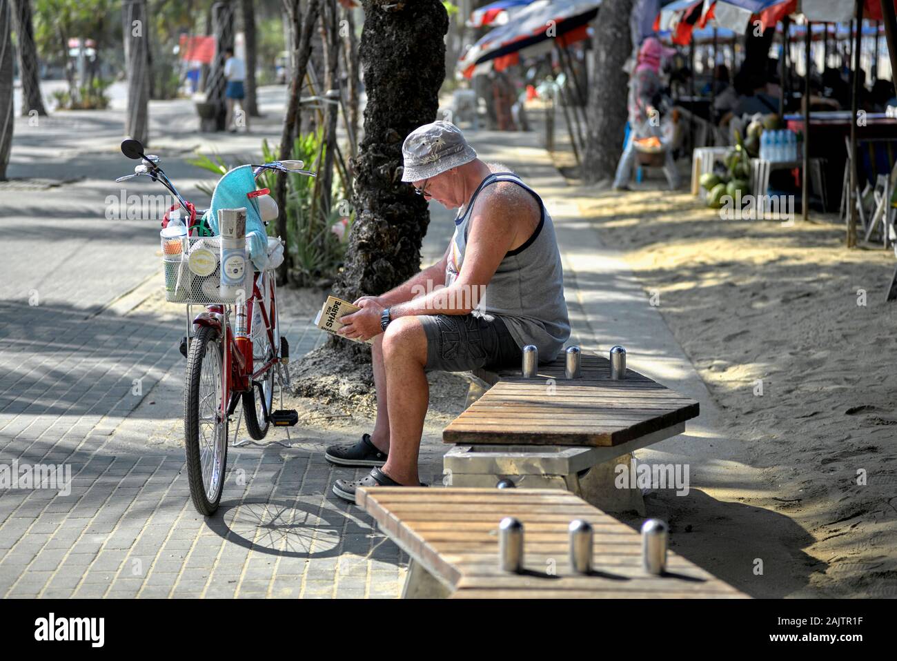 Mann allein draußen entspannen und ein Buch lesen mit seinem Fahrrad in der Nähe stehende Stockfoto