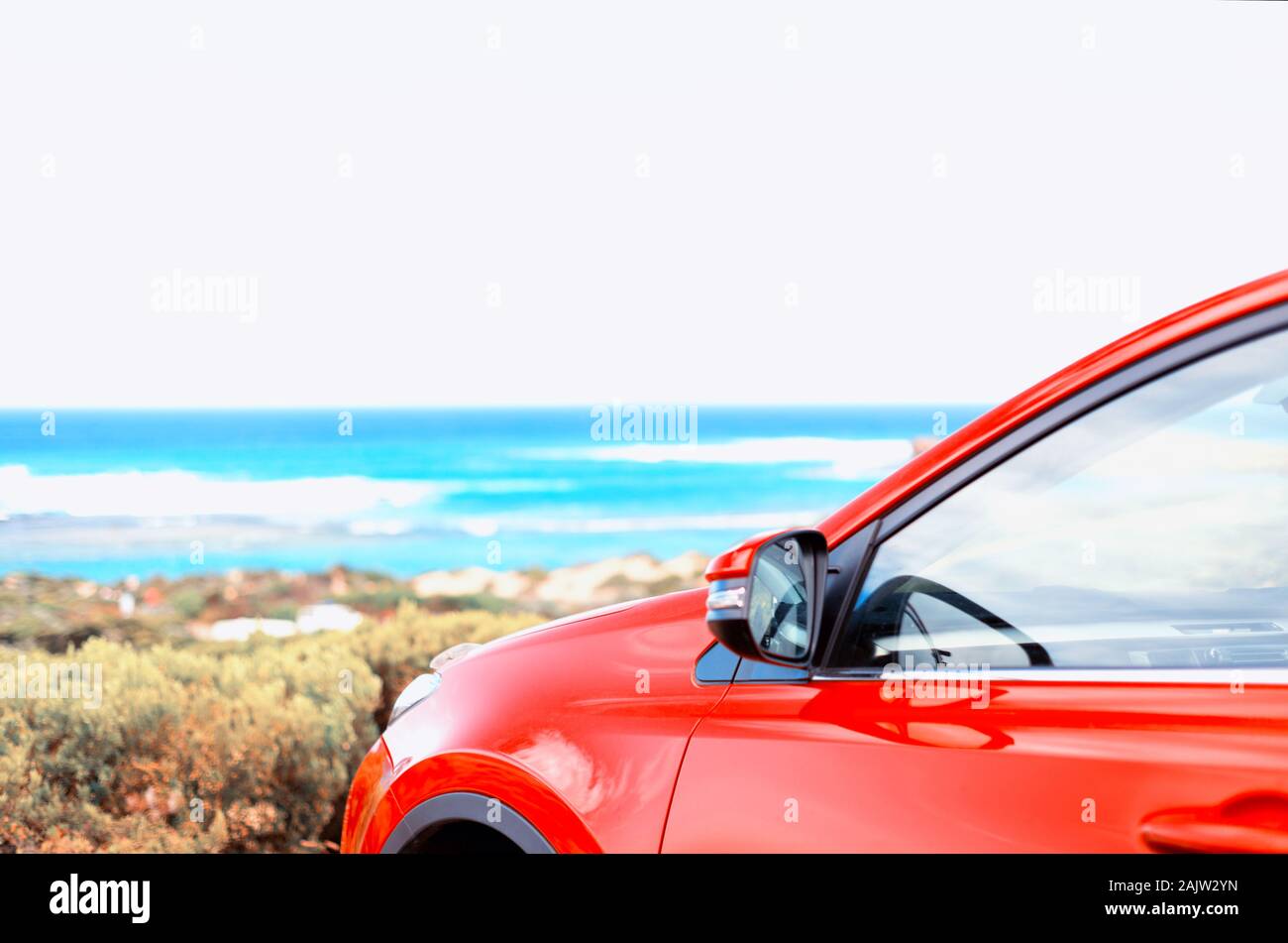 Ein Foto von einem hellen roten Auto neben dem Strand. Auto suchen auf dem Wasser. Stockfoto