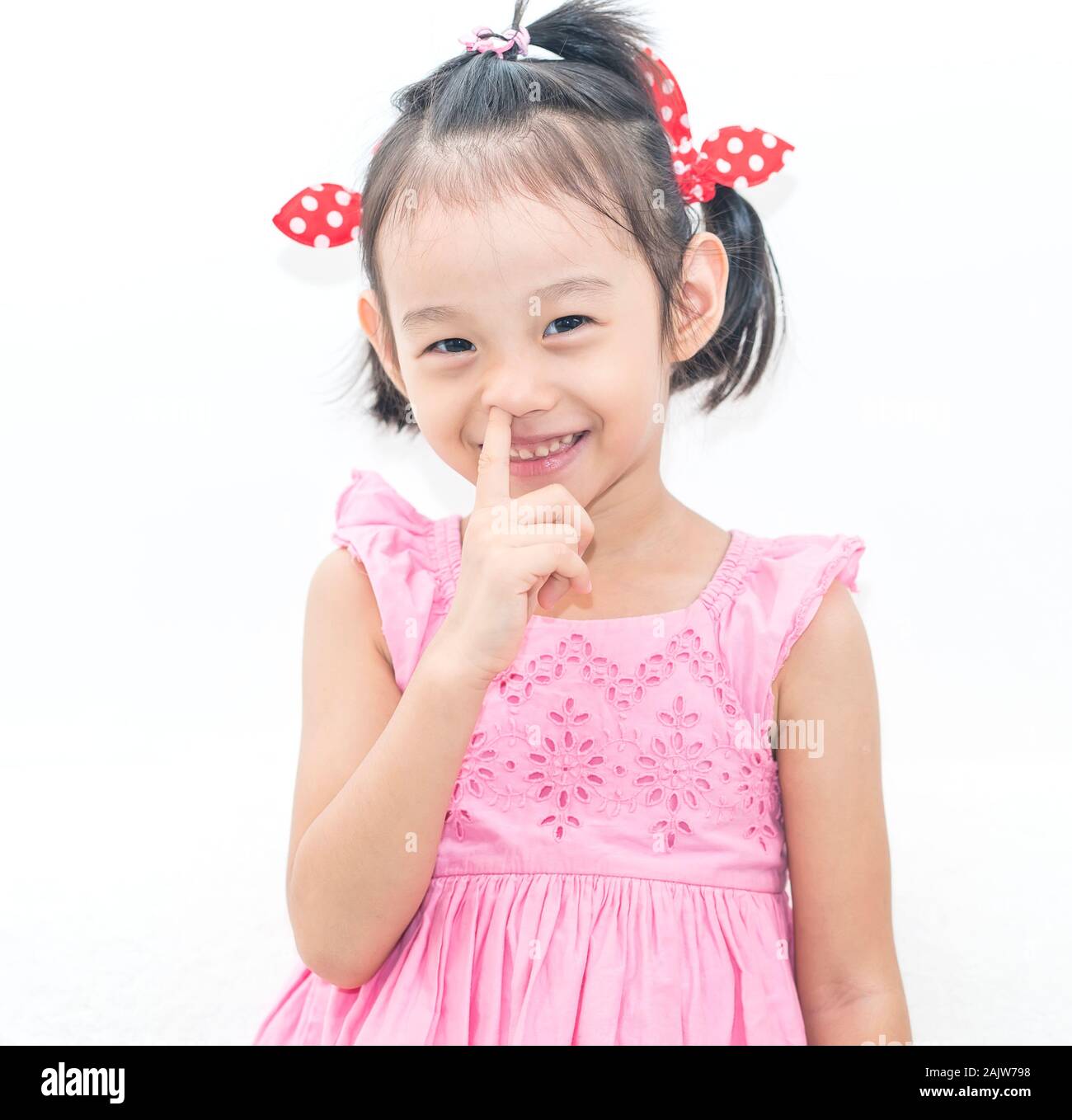 Kleine asiatische junge Mädchen mit Pokes einen Finger in der Nase Stockfoto