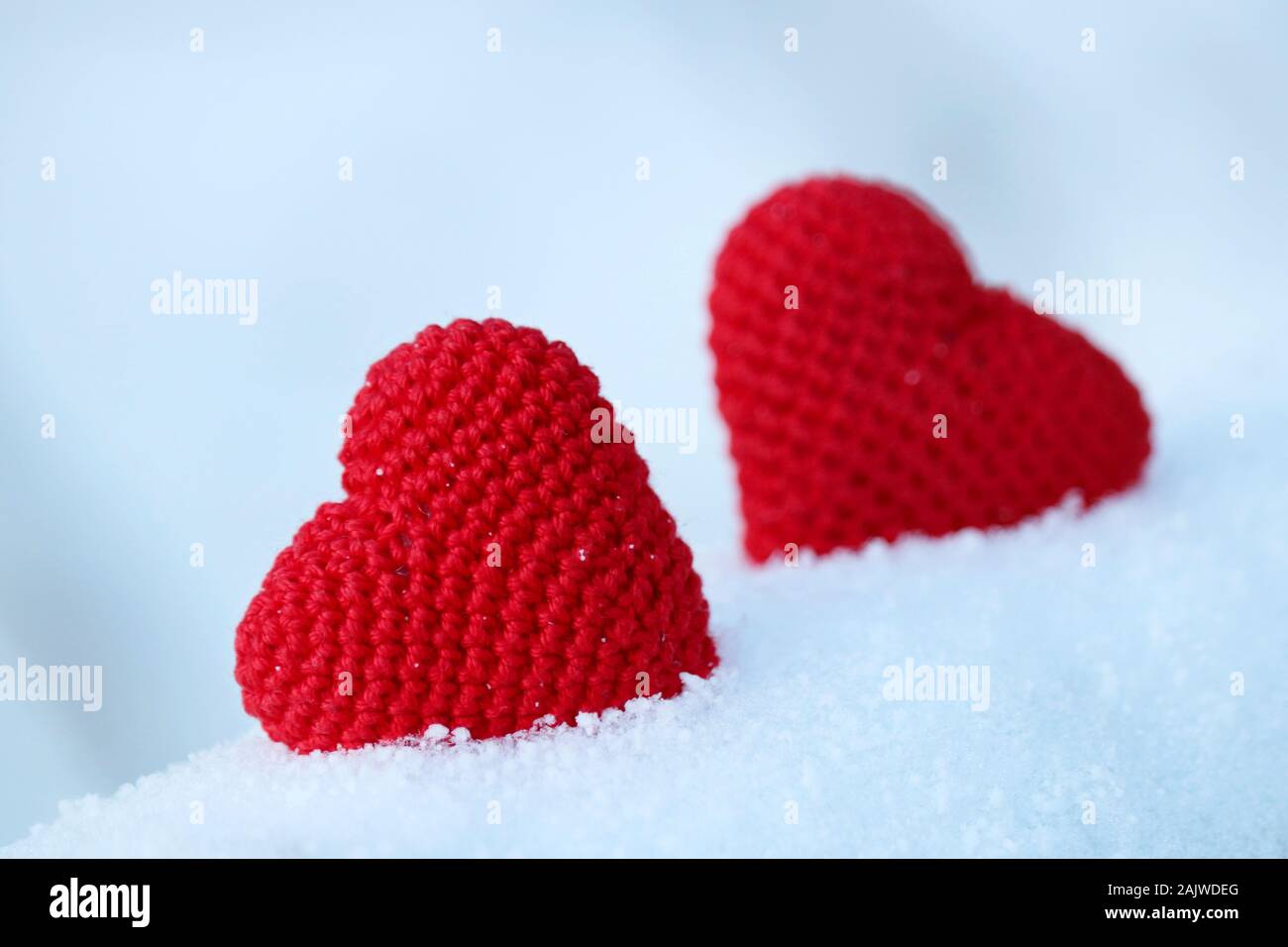 Valentinstag Herz, Grußkarte, zwei Rote gestrickt, Symbole der Liebe im Schnee. Hintergrund für romantische Veranstaltung, Feier oder Winter Wetter Stockfoto