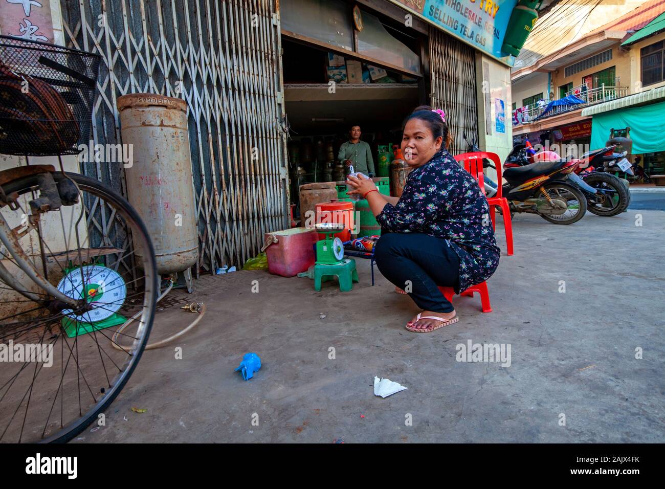 Eine asiatische Frau mittleren Alters arbeitet als Verkäufer im Einzelhandel Propan refill Center auf einem Bürgersteig in einem Geschäft in Kampong Cham, Kambodscha. Stockfoto