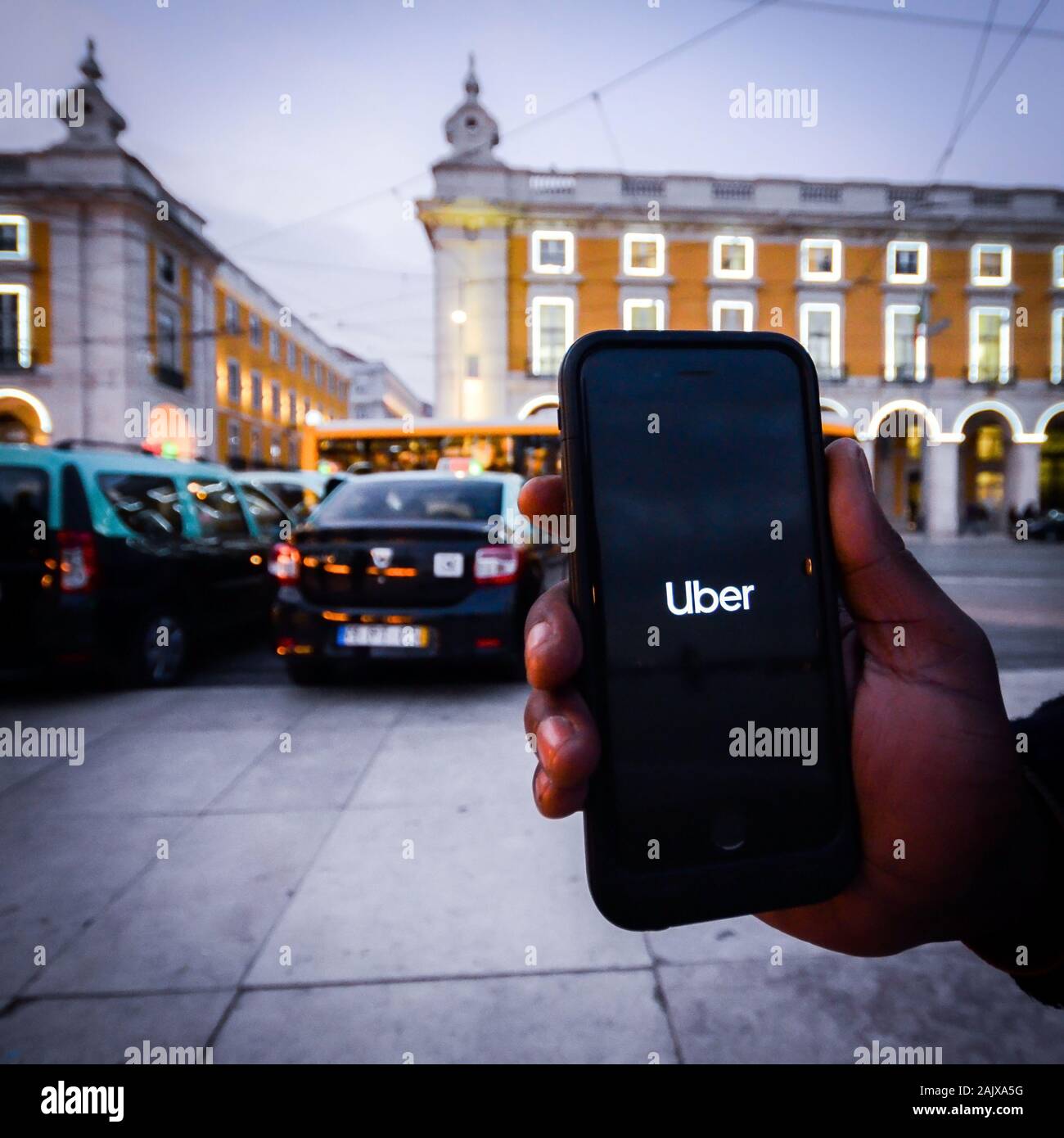 Lissabon, Portugal - Jan 3, 2010: Illustrative Redaktion eines Menschen Hilfestellung ein Smartphone mit ein Uber app Vor geparkten Taxis. Uber ist Smartphone Stockfoto