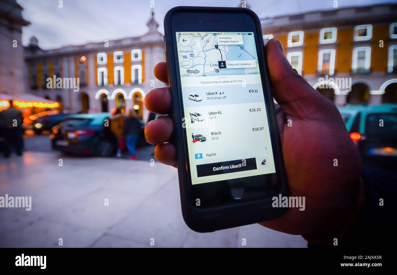 Lissabon, Portugal - Jan 3, 2010: Illustrative Redaktion eines Menschen Hilfestellung ein Smartphone mit ein Uber app Vor geparkten Taxis. Uber ist Smartphone Stockfoto